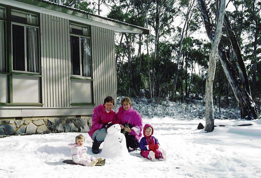 A family making a snowman beside a chalet